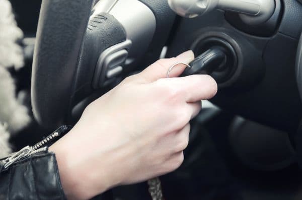 Closeup inside vehicle of hand holding key in ignition, start engine key