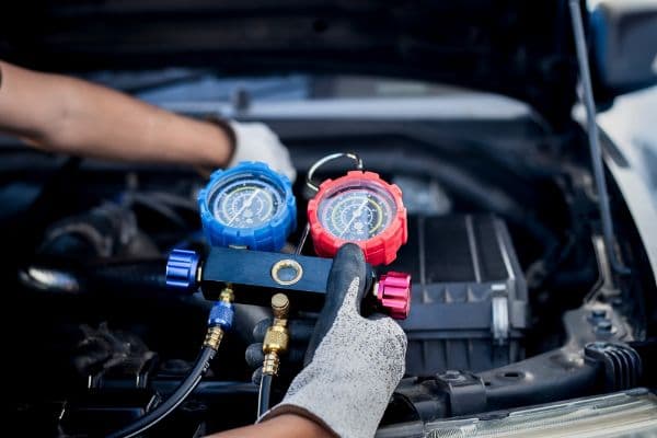 air conditioning technician, checks refrigerant and refills air conditioning on vehicle