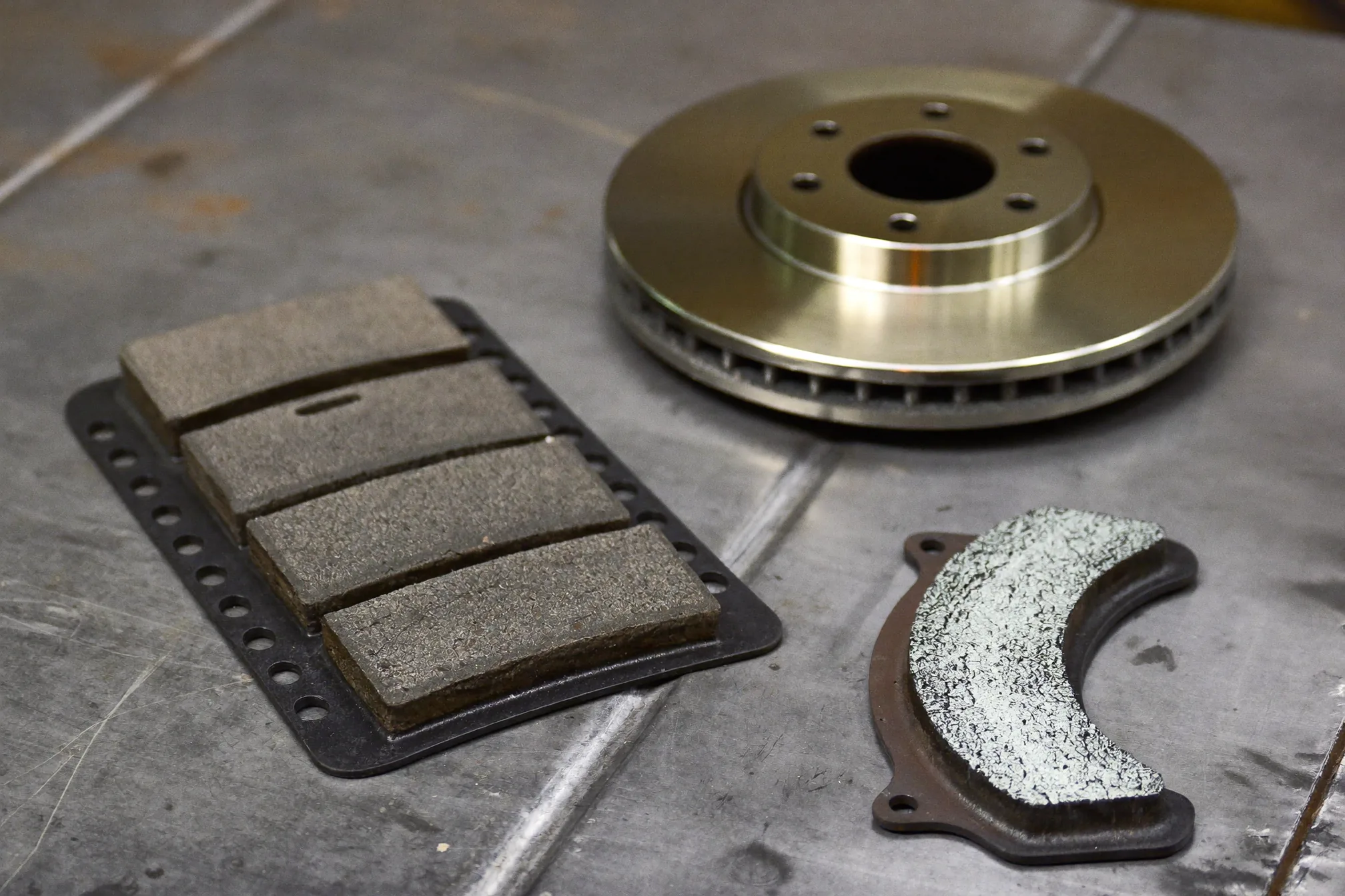 Illustration of new brake pads and a rotor on a workbench, parts that affect brake pad replacement cost